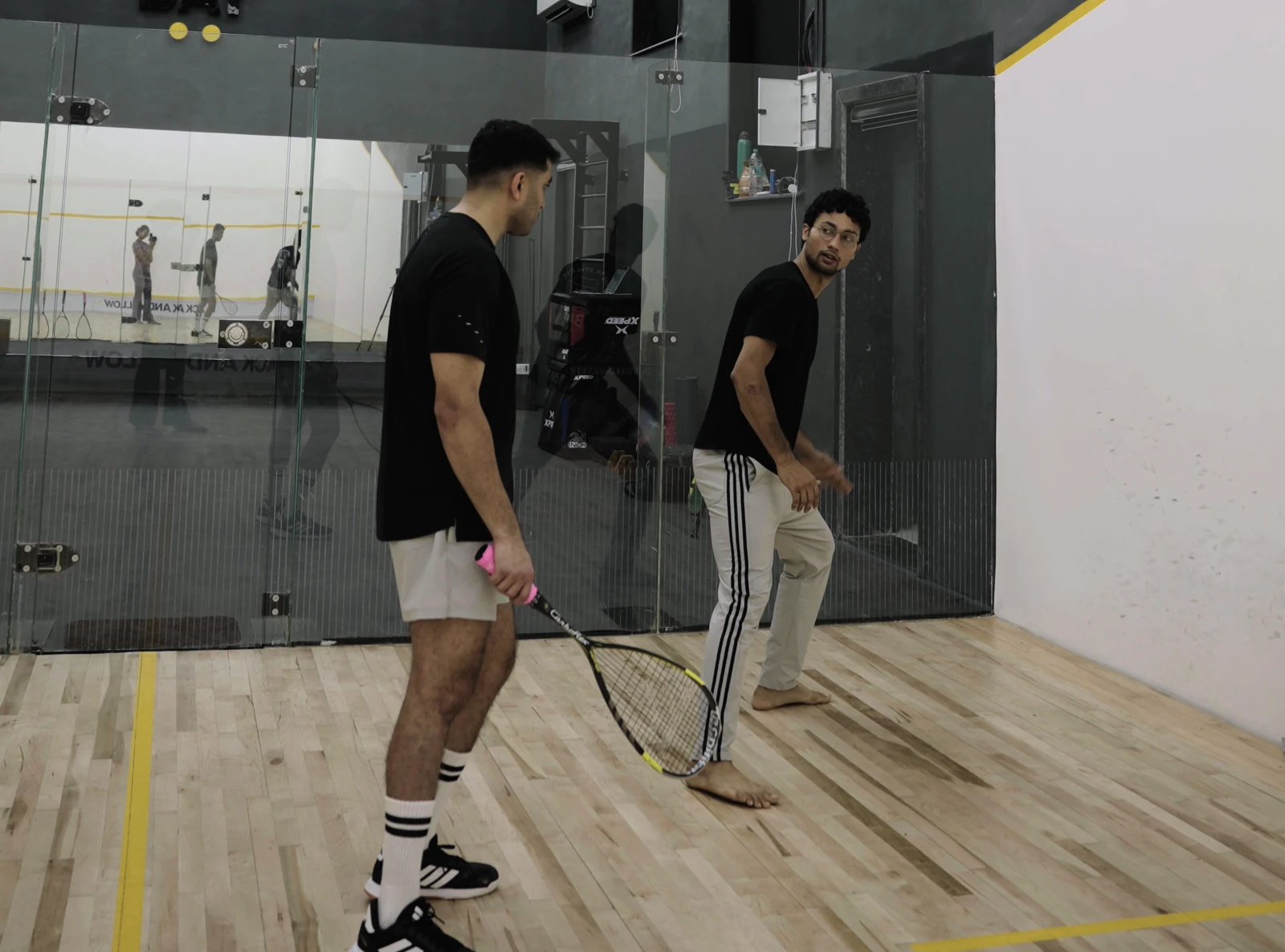 A coach giving a player feedback on the BAY squash court.